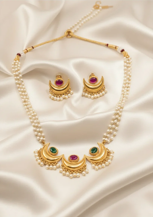 Gold plated Chandrakor pearl necklace with ruby and green stones and stud earrings on ivory satin