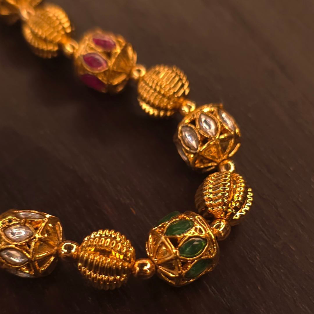 Detail of red, green and white enamel meenakari beads on long gold plated necklace