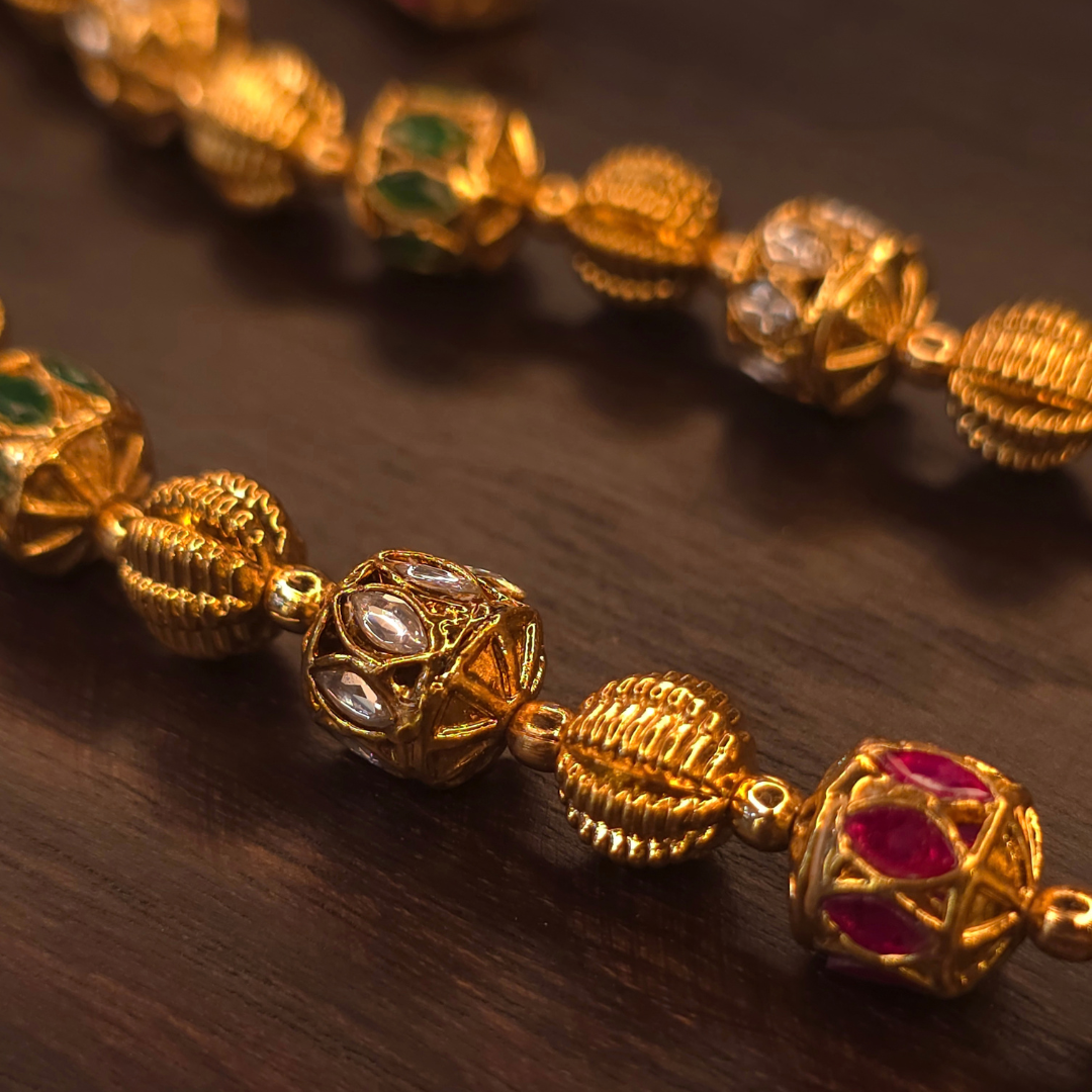 Close-up of meenakari beads with kundan and ruby stones on antique gold necklace