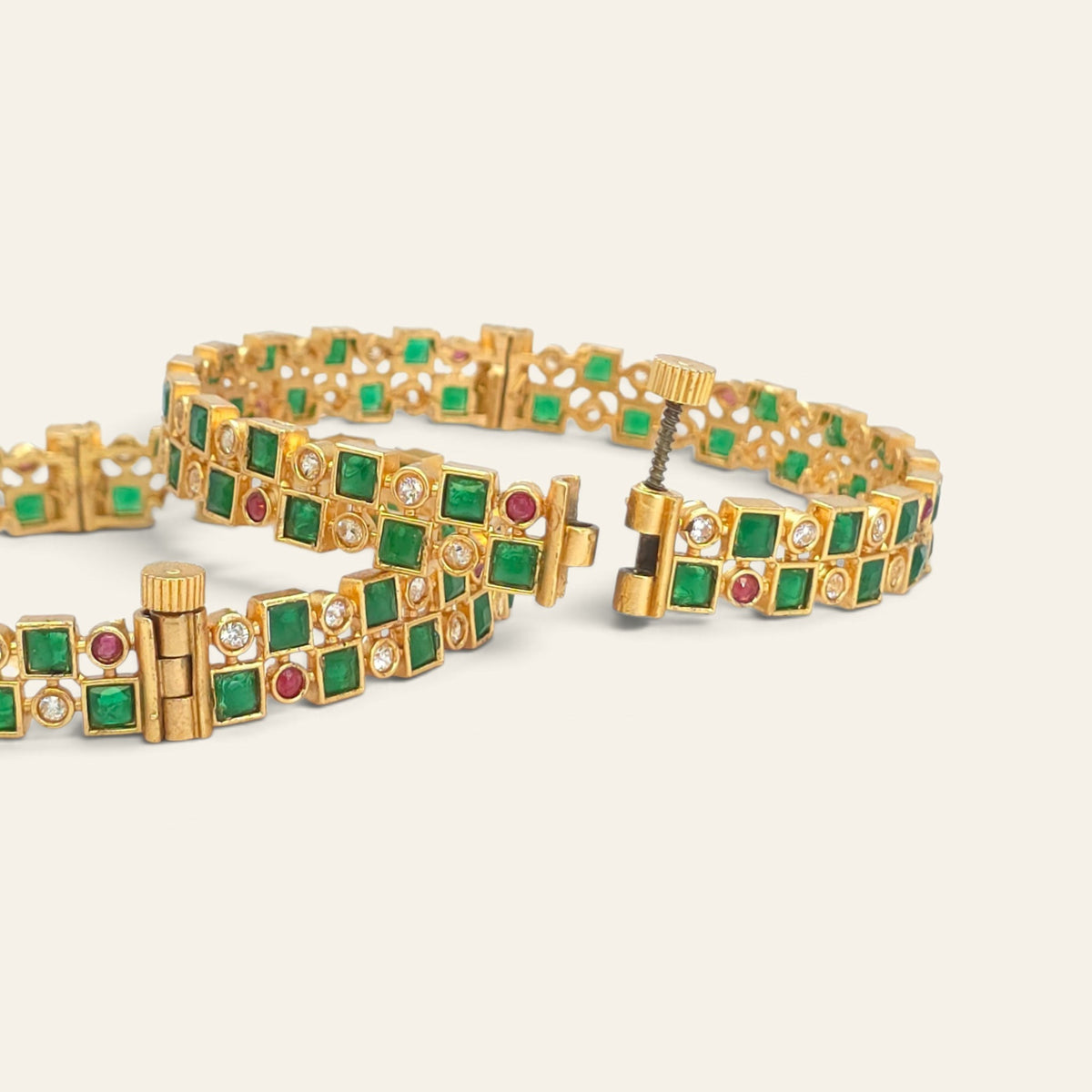 Emerald green gold plated bangles with ruby accents, checkerboard pattern, pair lying flat