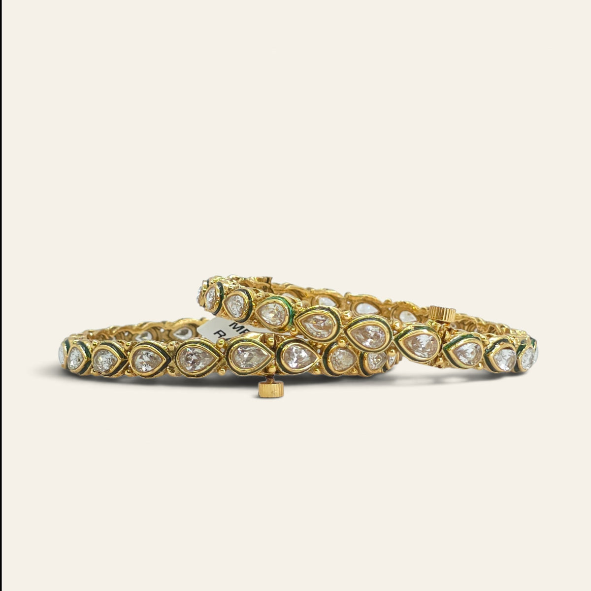 Close-up of white kundan pear-cut stones with green enamel outline on gold plated bangles