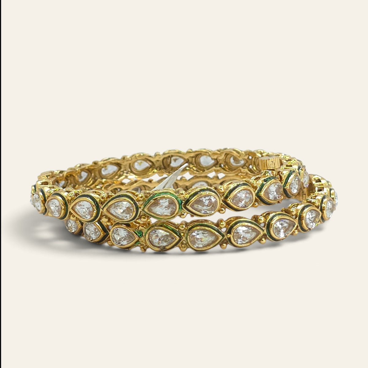 Pair of white kundan gold plated bangles standing upright, front view
