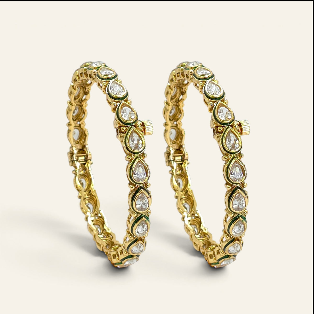 White kundan pear drop gold plated bangles, pair lying flat crossed