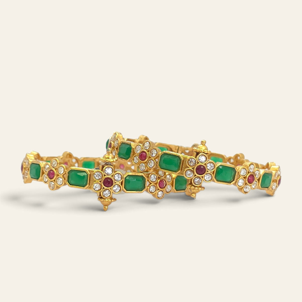 Emerald green floral ruby gold plated bangles, pair lying flat overlapping