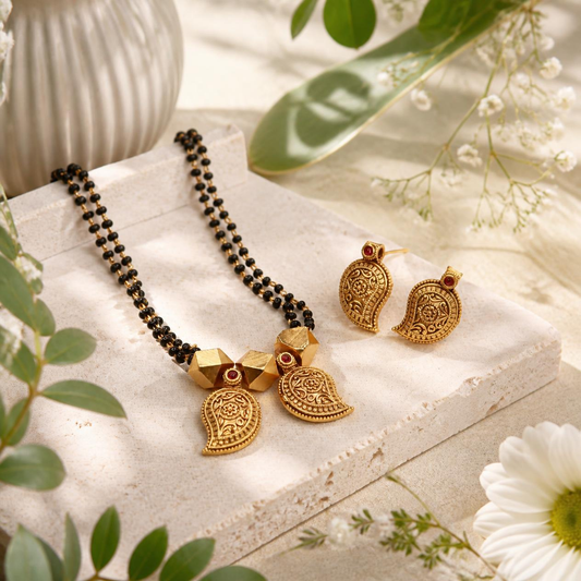 Close-up of antique gold paisley mango mangalsutra pendants with hand-engraved floral scroll motifs and deep red ruby cabochon detail