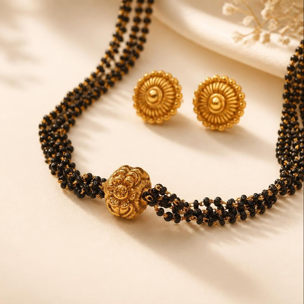 Gold plated black bead mangalsutra with multi-strand design and floral centerpiece bead, paired with circular stud earrings