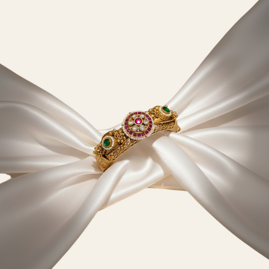 Jija Jewellery Heritage Glow Kundan Kada featuring gold-plated metal, ruby and emerald stones on white silk fabric.