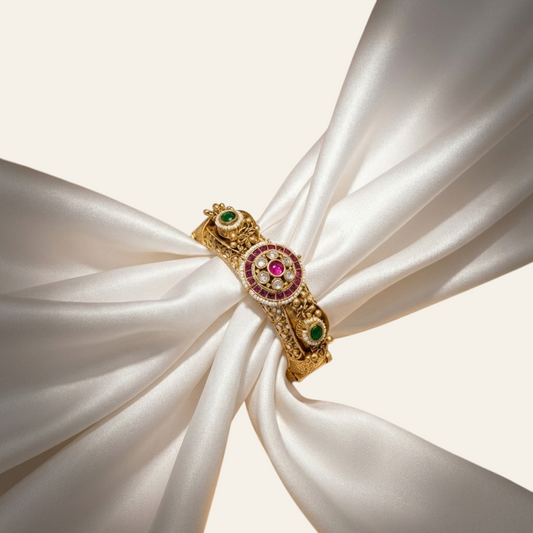 Jija Jewellery gold plated Rajwada Kundan Kada with ruby and emerald stones on a white silk fabric background