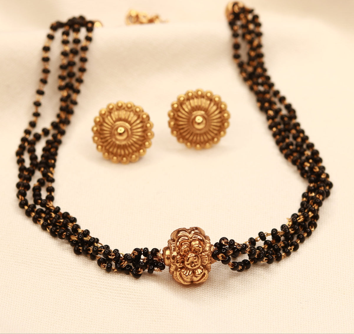 Close-up of black bead mangalsutra with gold plated floral pendant, ethnic bridal jewellery by Jija Jewellery