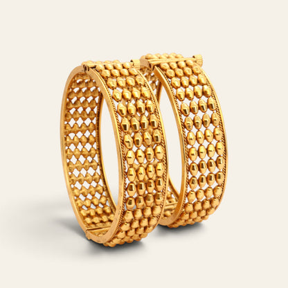 Pair of gold-tone openwork bangles showing hinged screw closures