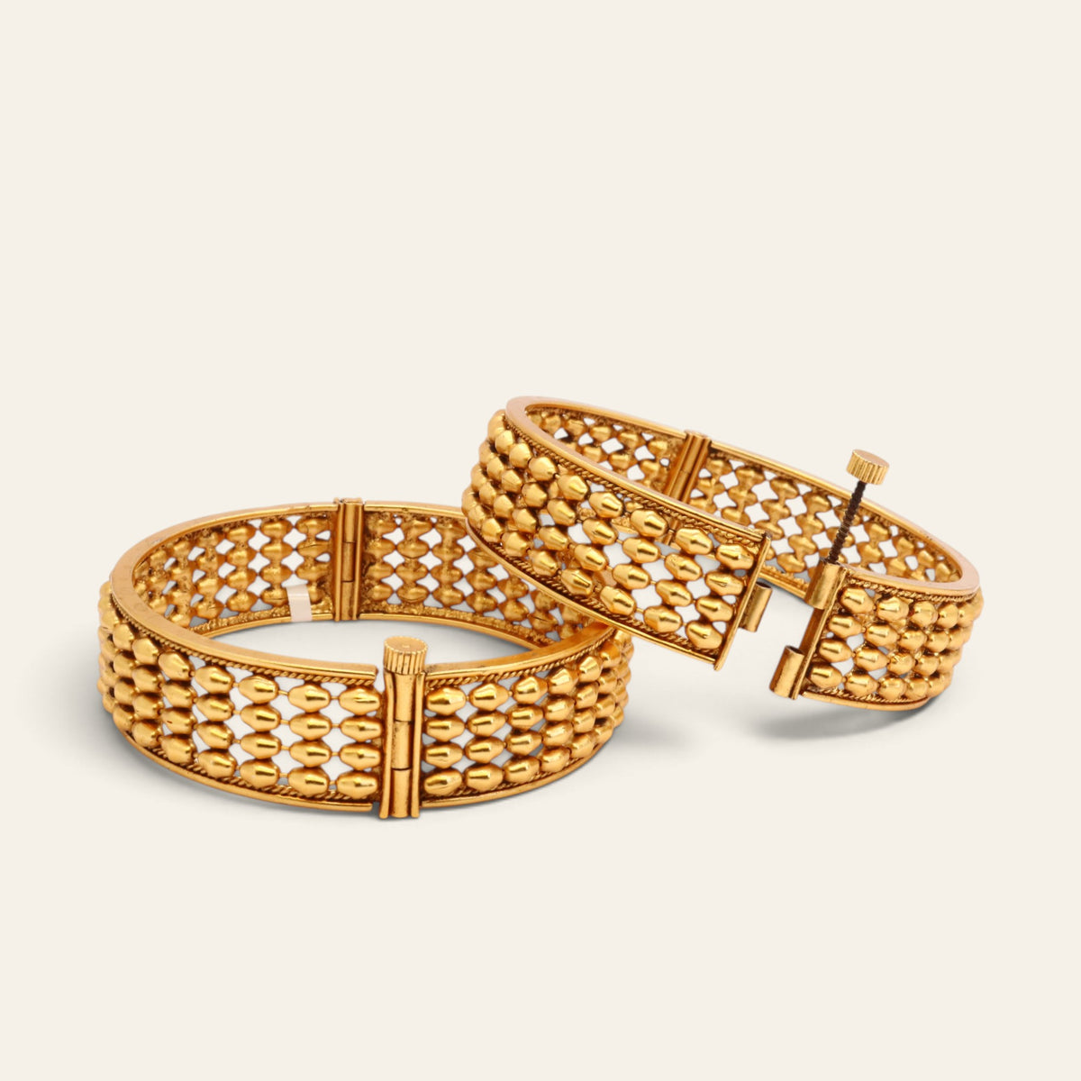 Angled view of matching gold-tone openwork beaded bangles
