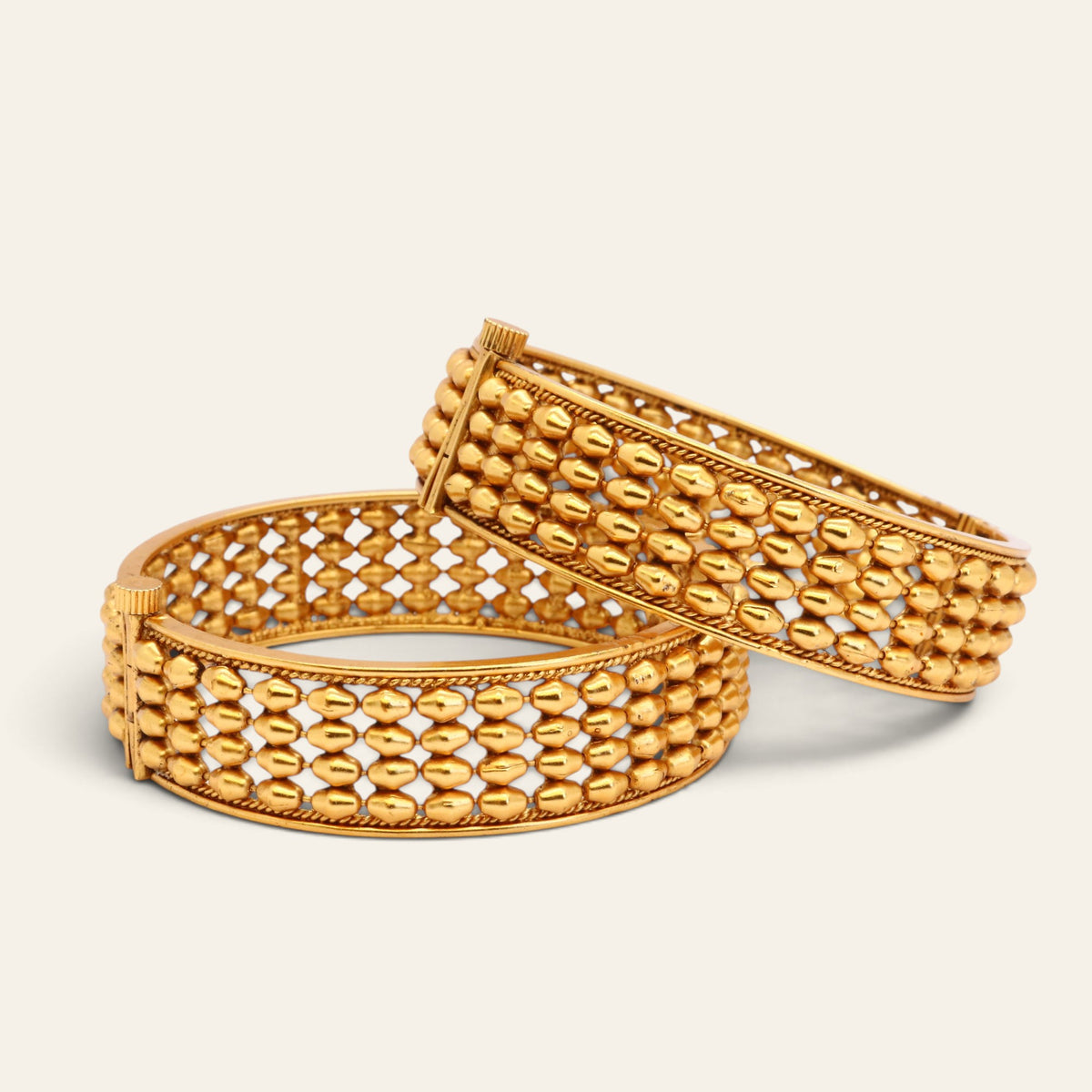 Two wide gold-tone openwork bangles standing upright