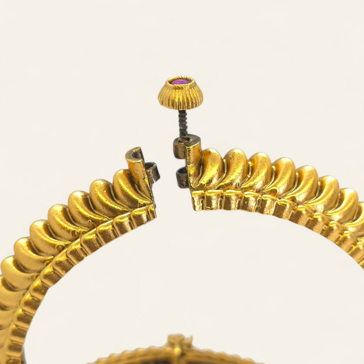 Two gold-plated Shindeshahi Tode bangles displayed upright with red stone accents