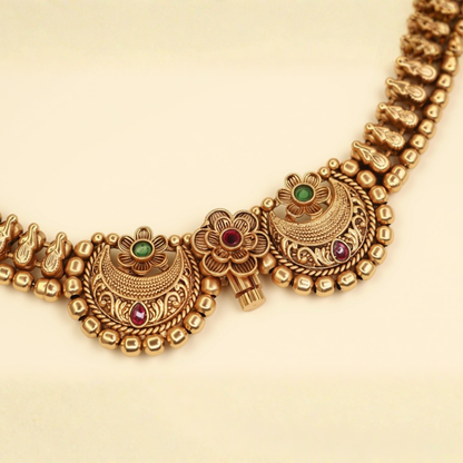 Close-up of Chandbali choker necklace twin crescent moon pendants with ruby and emerald stones and gold bead border