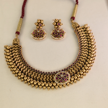Close-up of ruby-red kundan medallion centrepiece with pearl accent on Vazartik Thushi antique gold necklace