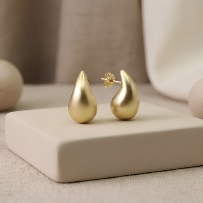 Gold teardrop drop stud earrings showing smooth brushed matte finish, close-up