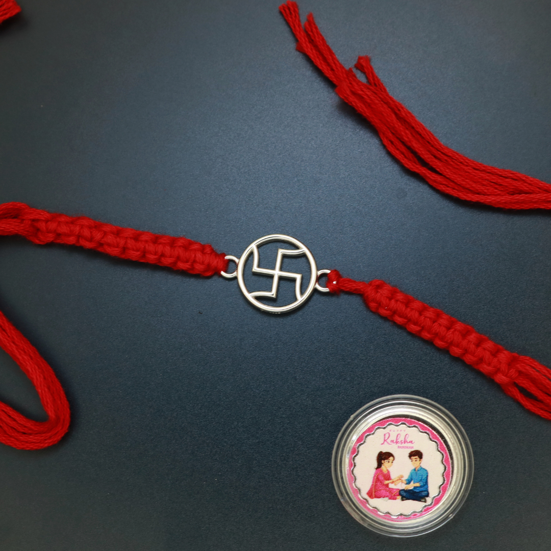 Sterling silver Swastik rakhi in open-work circular design, side view on red thread