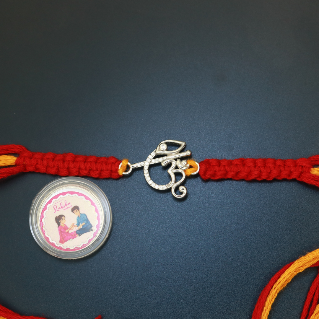 Sterling silver Om Ganesha rakhi studded with zircon on braided red and yellow thread