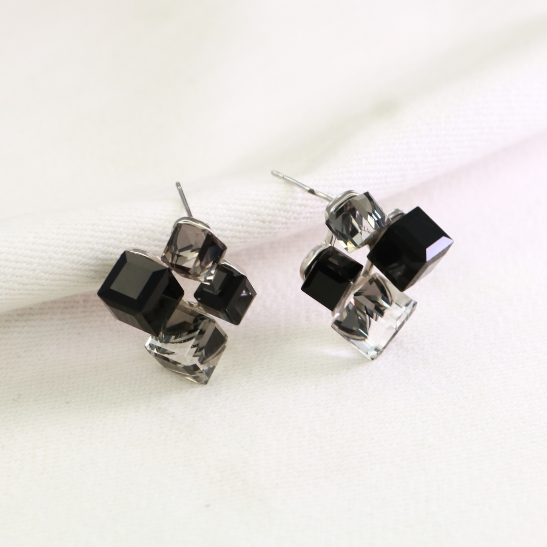 Black and grey crystal cube stud earrings in silver-tone setting on cream fabric