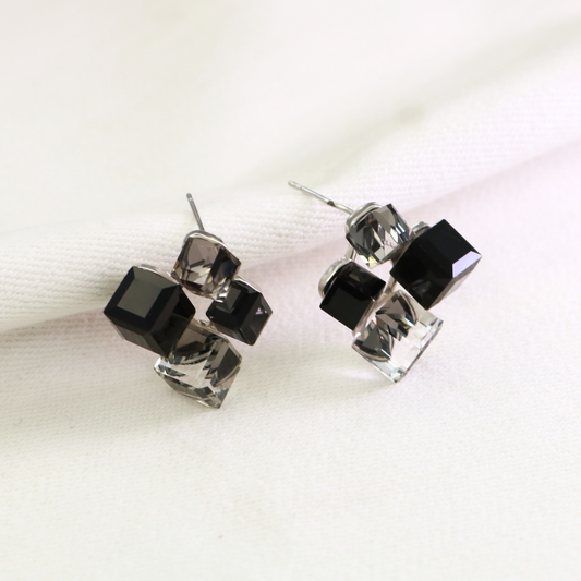 Black and grey crystal cube stud earrings in silver-tone setting on cream fabric