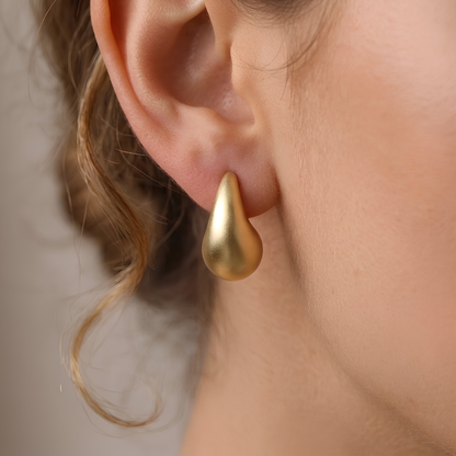 Sculptural matte gold waterdrop teardrop stud earrings, front view on neutral background