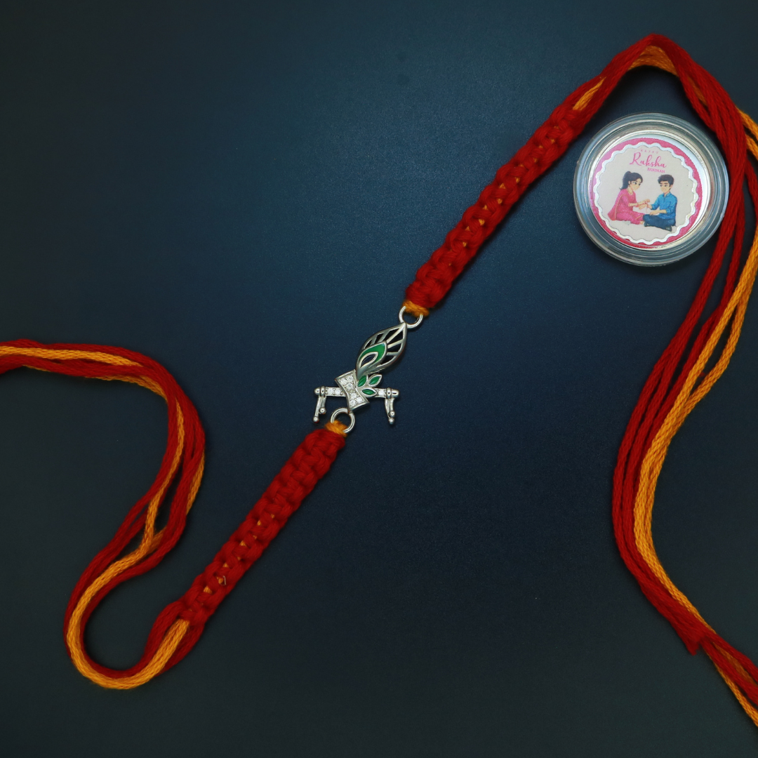Sterling silver Morpankh rakhi with green meenakari peacock feather and zircon base on red and yellow thread