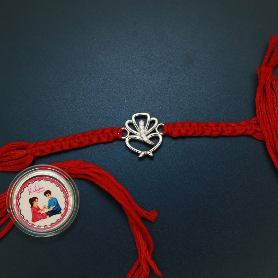 Sterling silver Ganesha rakhi with flowing curved form and zircon-set trunk on braided red thread