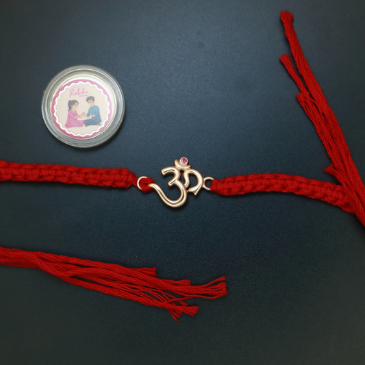 Rose gold plated sterling silver Om rakhi with ruby-red stone on braided red thread