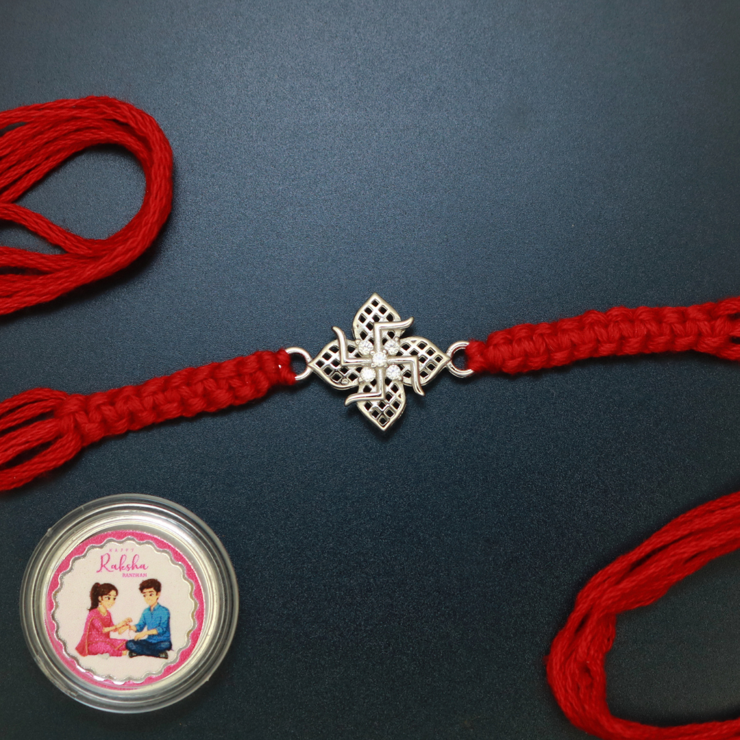 Sterling silver jali filigree Swastik rakhi with four-petal floral cut-work and zircon centre on red thread