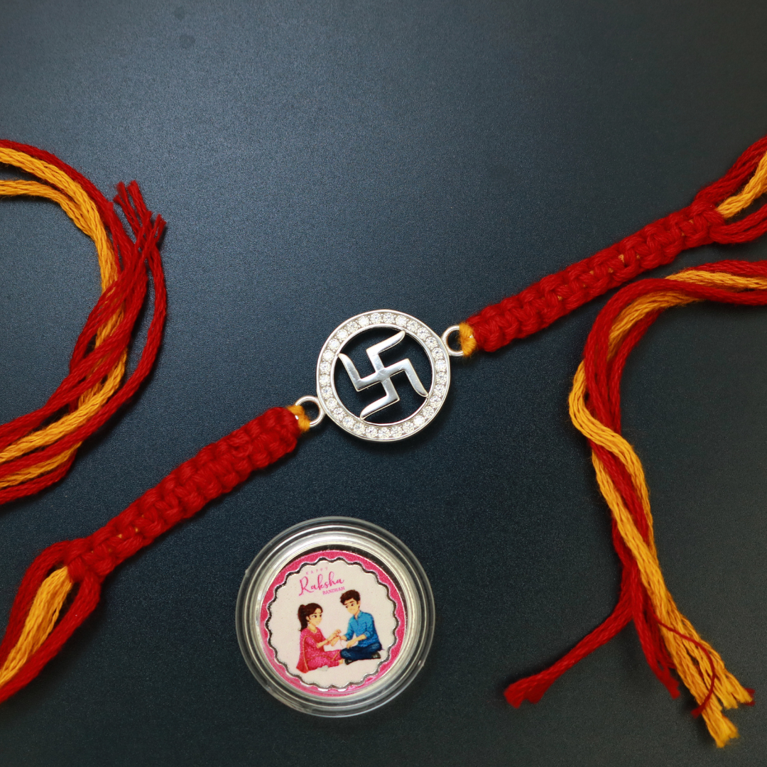 Sterling silver Swastik rakhi ringed by a full circle of zircon stones on red and yellow thread
