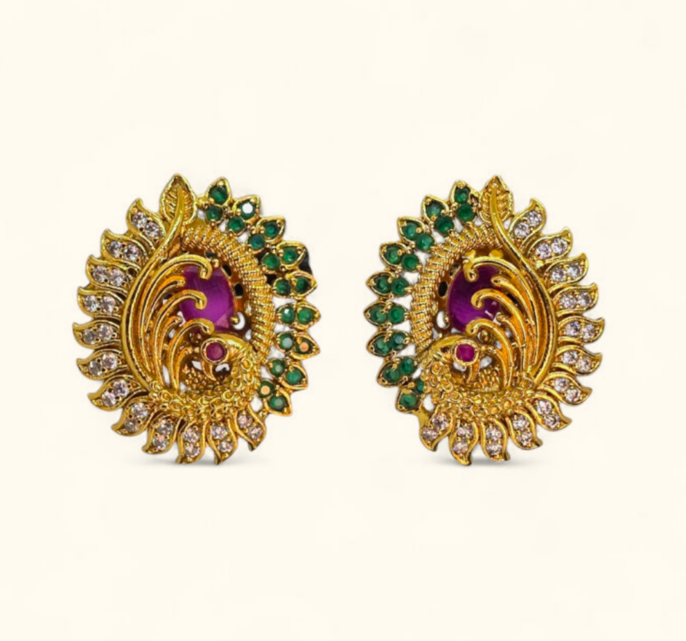 Gold plated peacock design stud earrings with green and magenta stones on white background