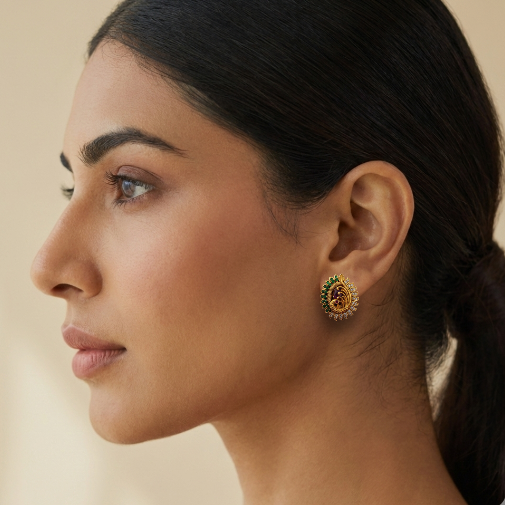 Side profile of woman wearing gold plated peacock stud earrings