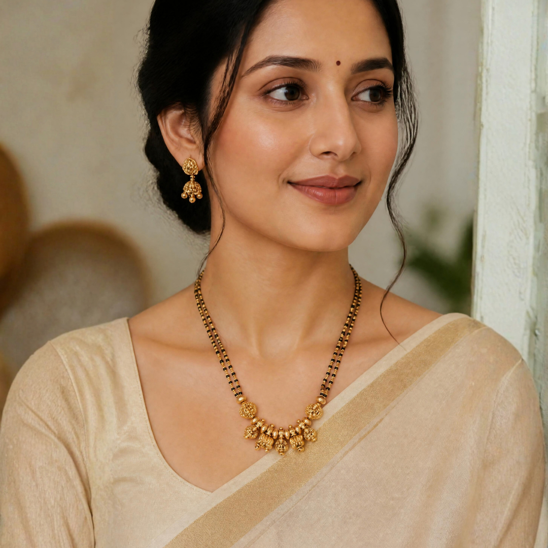 Woman wearing antique gold plated Lakshmi temple mangalsutra with double strand black beads and a cream saree – bridal and festive look