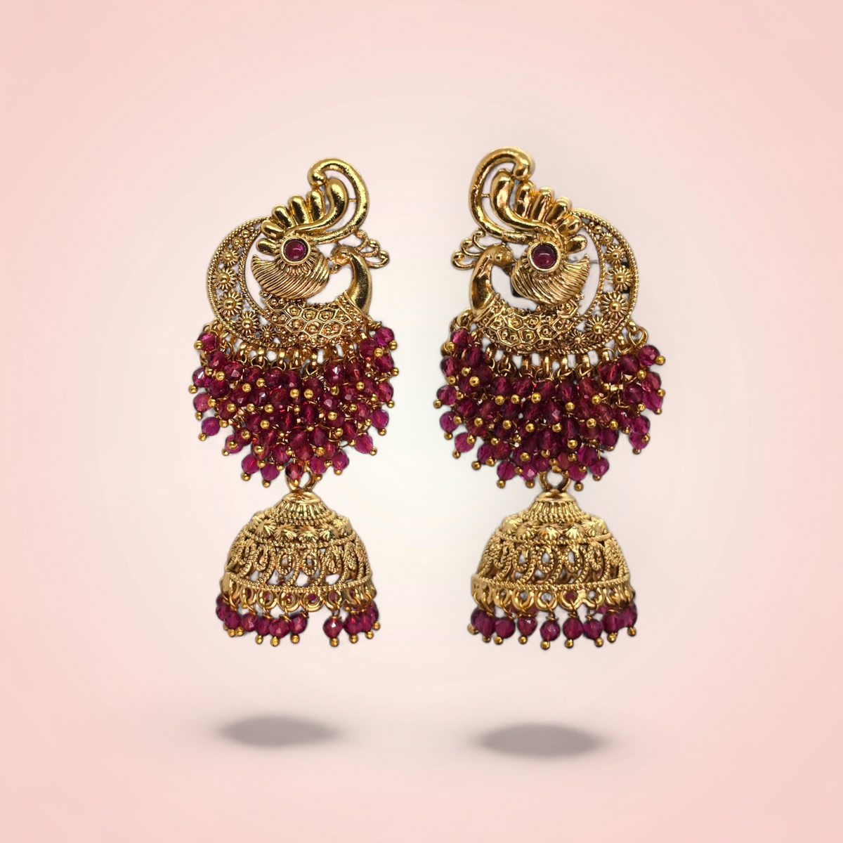 Pair of peacock red crystal jhumki earrings for weddings on pink background