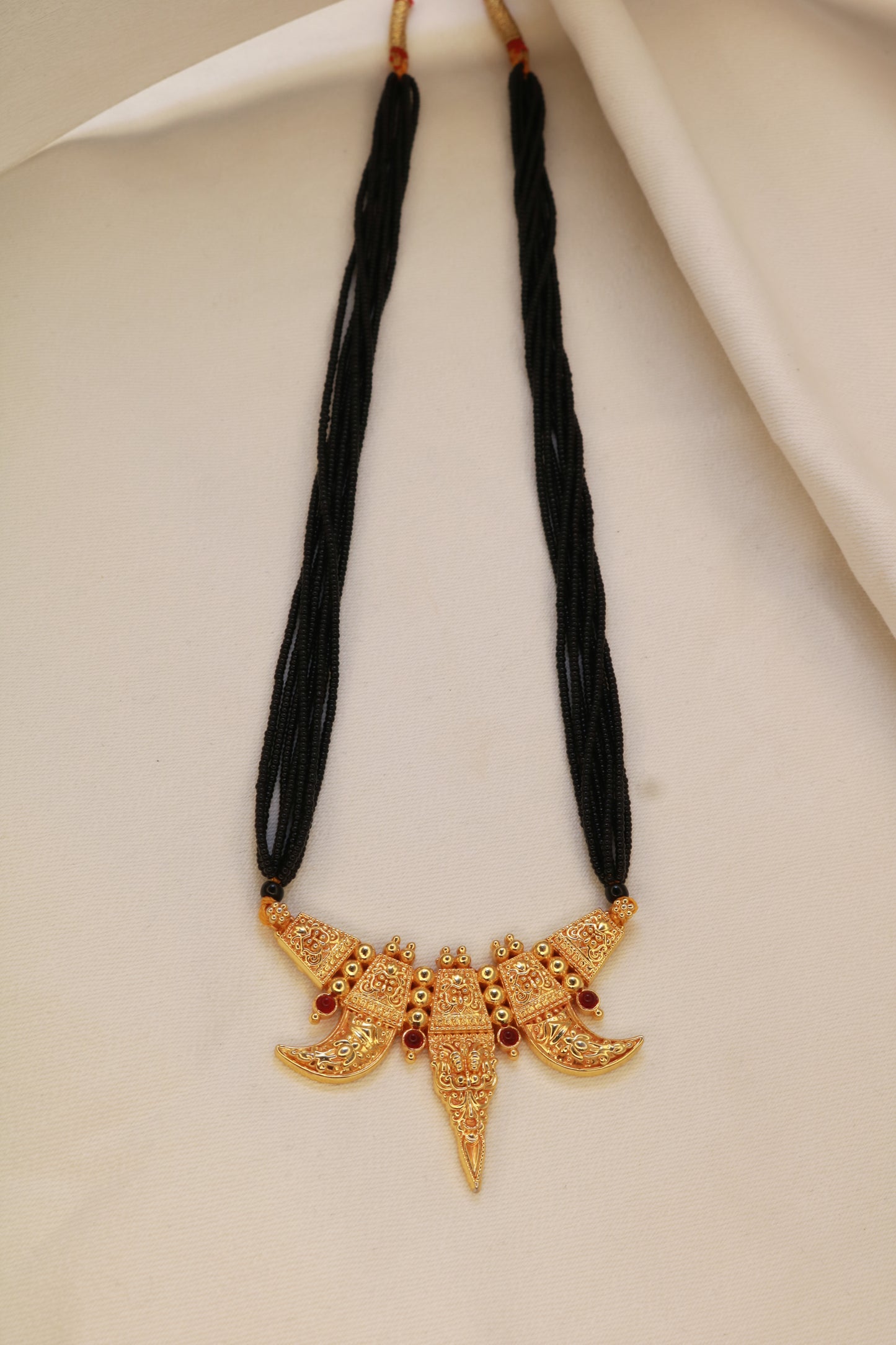 Traditional Maharashtrian Kirtimukh Mangalsutra flat lay – gold plated pendant with multi-strand black bead doori | Jija Jewellery Satara