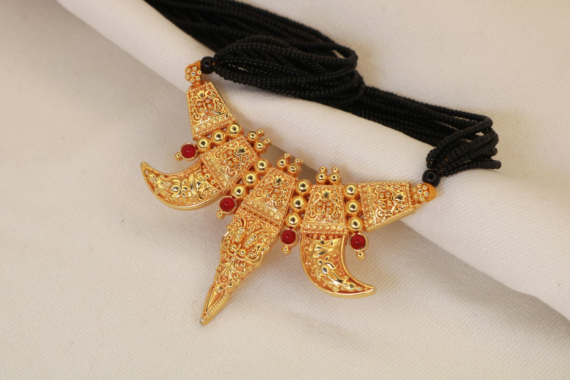 Close-up of Kirtimukh gold plated pendant with ruby accent stones and multi-strand black bead doori – Jija Jewellery