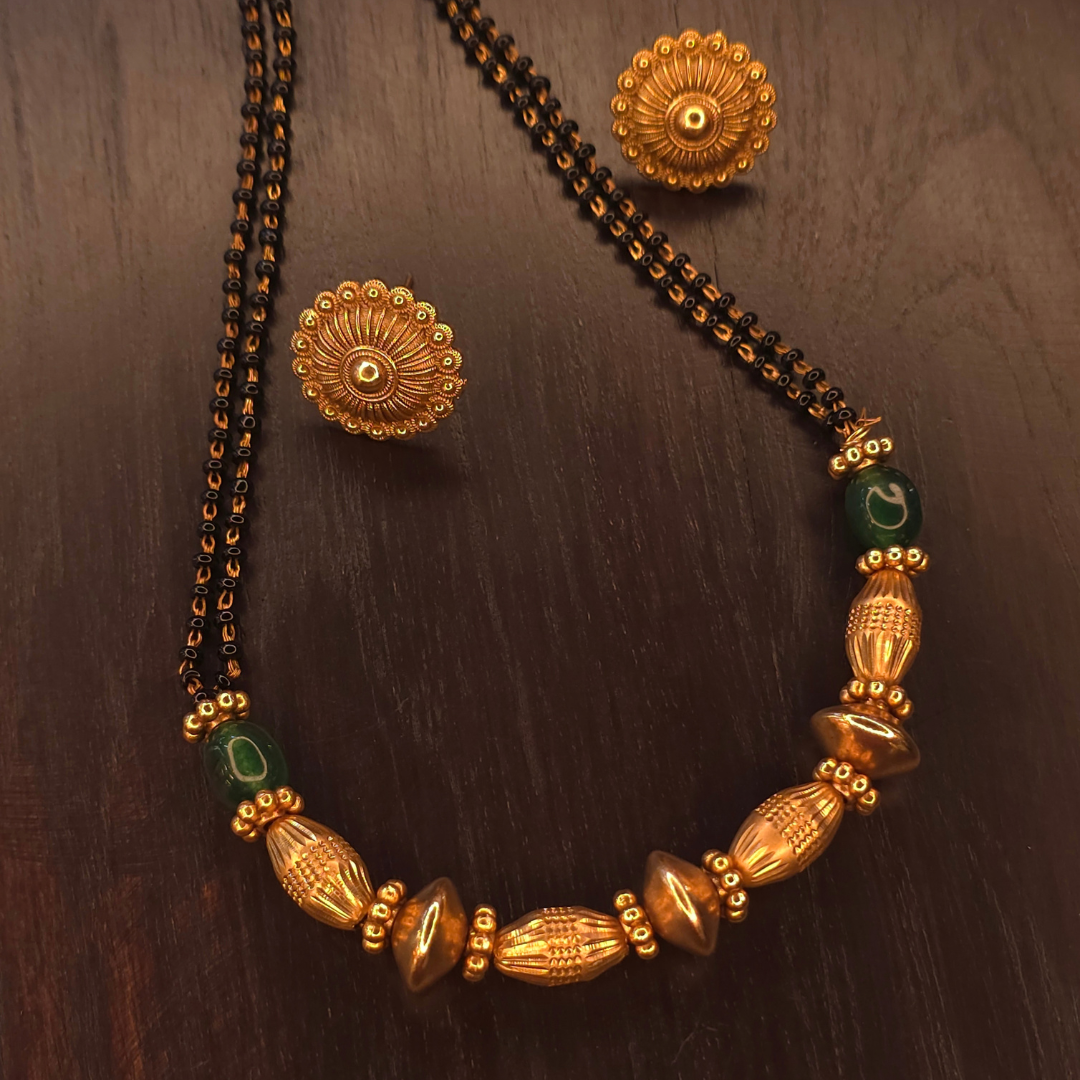 Close-up of green accent beads and sculpted gold-tone centre beads on gold-plated mangalsutra