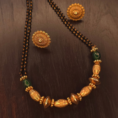 Close-up of green accent beads and sculpted gold-tone centre beads on gold-plated mangalsutra