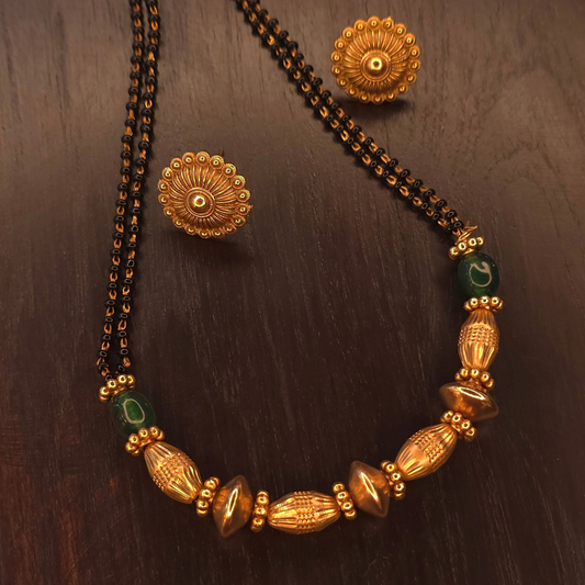 Close-up of green accent beads and sculpted gold-tone centre beads on gold-plated mangalsutra