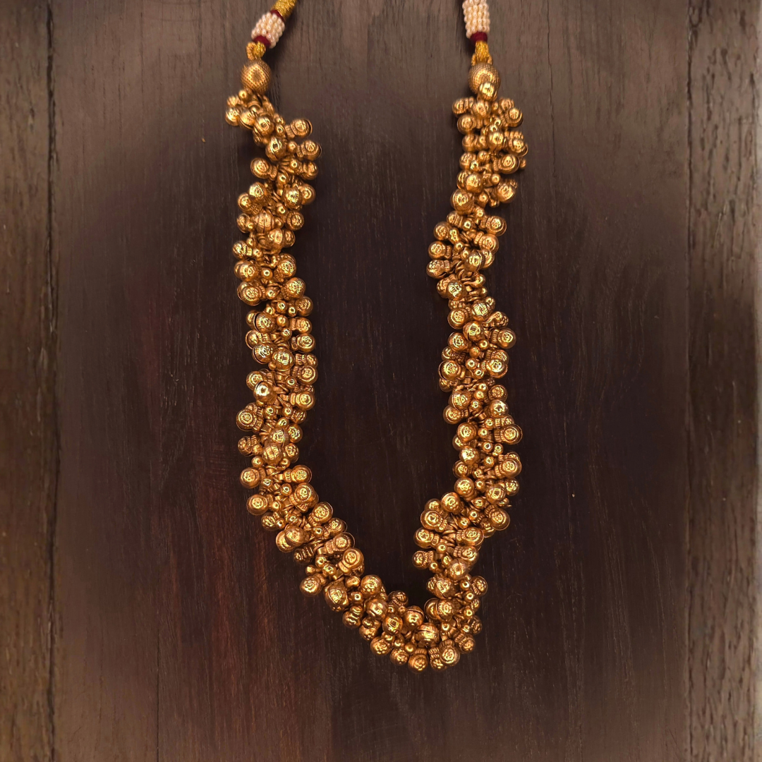 Close view of dense gold ghungru bell beads forming a thick textured long necklace