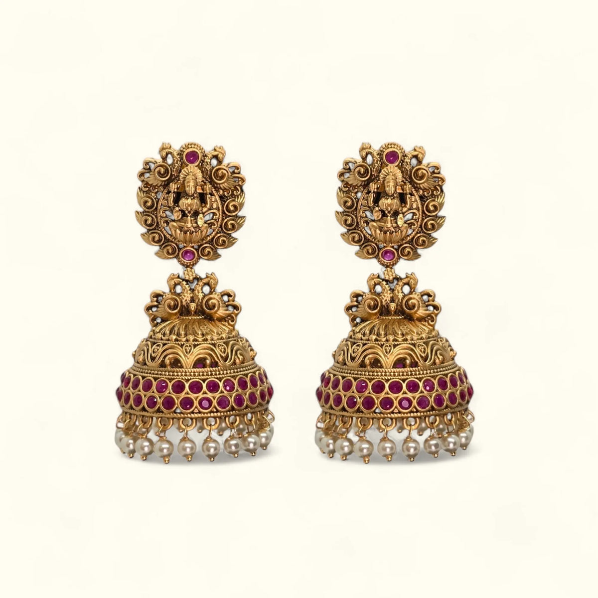 Gold plated temple zumka earrings with ruby stones and pearl drops on white background